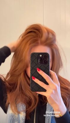 a woman taking a selfie with her cell phone in front of her face and red hair