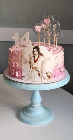 a decorated cake with pink frosting and flowers on top is sitting on a blue pedestal