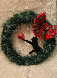 a black cat standing next to a christmas wreath