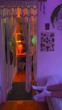 a person laying on a bed in a room with purple lighting and hanging curtains over their head