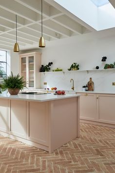 a large kitchen with an island in the middle and gold pendant lights hanging from the ceiling