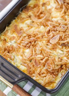 a casserole dish with cheese and onions in it on a green and white checkered table cloth