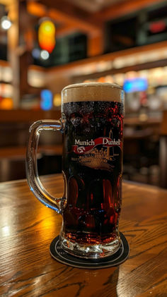 a glass of beer sitting on top of a wooden table