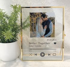 a gold frame holds a photo of a couple on their wedding day and is next to a potted plant