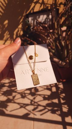 a person holding up a small gold necklace