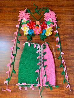 two pieces of crocheted clothing with flowers on them sitting on a wooden floor