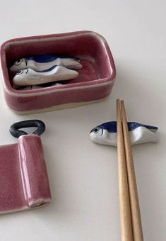 three bowls with chopsticks and two figurines in them on a table