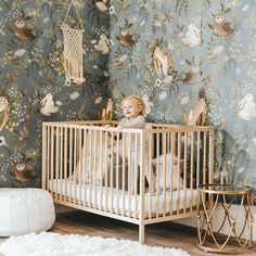 a baby sitting in a crib next to a wallpaper