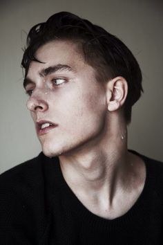 a close up of a person wearing a black shirt and looking off to the side