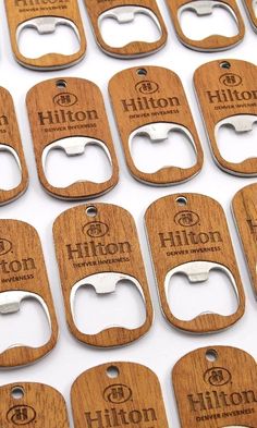 many wooden bottle openers are lined up on a table with the words hilton engraved on them