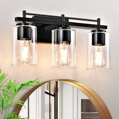 three light bathroom fixture with clear glass shades and gold trim around the edges, on a white wall