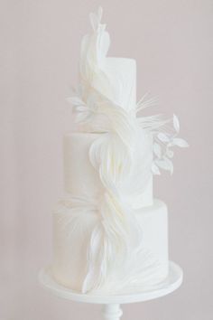 a white wedding cake with feathers on top