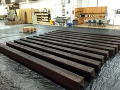 the floor is covered with black tarp and wooden planks in an industrial building