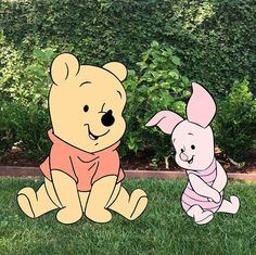 winnie the pooh and piglet paper cut outs sitting on grass in front of bushes