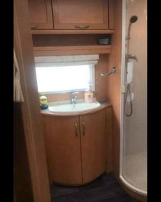 the inside of a small bathroom with a sink and shower in it's corner