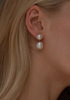 a close up of a woman's ear with two pearls on the end of it