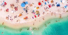 an aerial view of people on the beach with umbrellas and chairs in the water