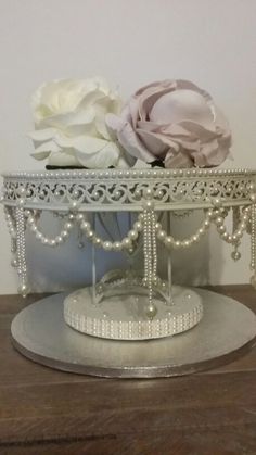 there is a silver tray with flowers on it and pearls around the edges, as well as beaded trim