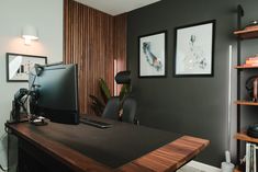 a desk with a computer monitor on top of it next to a book shelf filled with books