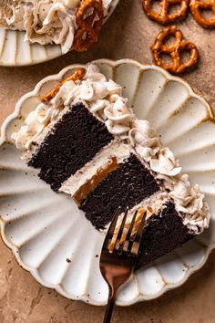 a piece of cake on a plate with a fork and some pretzels in the background