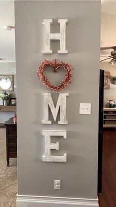 a sign that says home with a heart and wreath hanging on the side of it