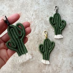 two green cactus keychains with tassels in the shape of heart shaped cactuses