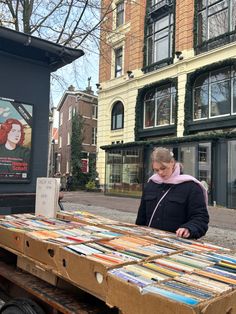 a woman standing next to a table full of books in front of a storefront