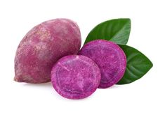 two purple potatoes with green leaves on the side