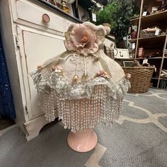 a pink lamp shade sitting on top of a wooden table next to a white cabinet