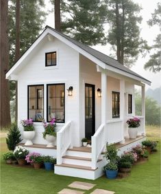 a small white house with potted plants on the front porch and steps leading up to it