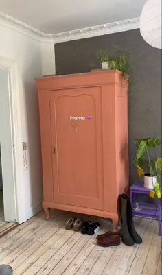 an orange cabinet sitting on top of a wooden floor next to a purple shelf and potted plant