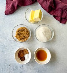 four bowls with different ingredients in them on a white counter top next to a red towel