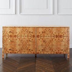 a wooden dresser sitting on top of a hard wood floor next to two white walls