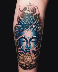 a tattoo on the leg of a person with a buddha head and lotus flower in it