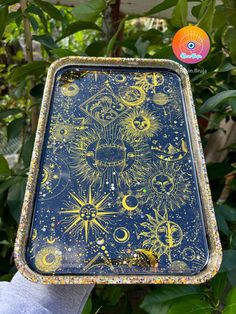 a hand holding up a tray with an image of the sun and stars on it