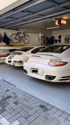 three porsches are parked in a garage with bicycles on the rack and one is white