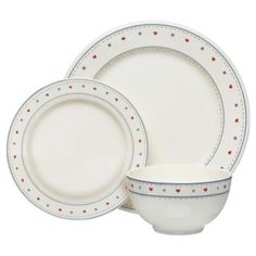 a set of white and blue dinnerware with red hearts on the rims,