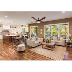 a living room filled with furniture next to a kitchen and breakfast nook area on top of a hard wood floor