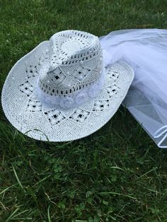 a white hat is laying on the grass with a veil around it's brim