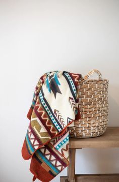 a basket sitting on top of a wooden table next to a blanket