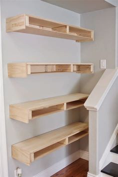 three wooden shelves on the wall above stairs