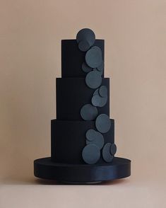 a three tiered black cake with circles on it