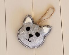 a cat ornament hanging from a string on a white wall with wood planks