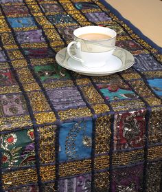 a cup of coffee sitting on top of a table covered in multicolored squares