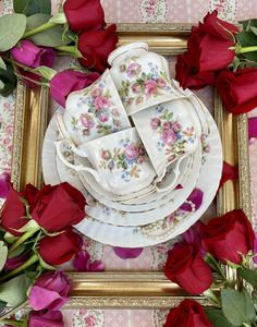 there is a table set with roses on it and plates in front of the frame