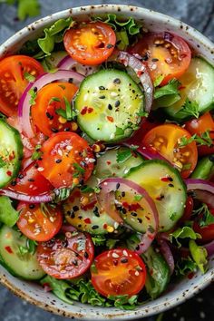 a white bowl filled with cucumber, tomatoes and red onion on top of a table