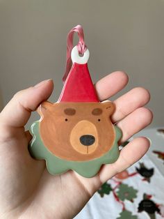 a hand holding a christmas ornament shaped like a bear