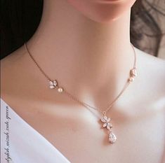 a close up of a woman wearing a necklace with flowers on the side and pearls hanging from it