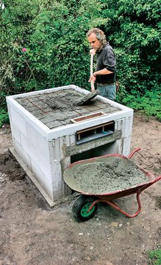 a man standing next to a wheelbarrow filled with cement