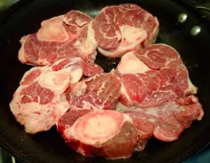 raw meat being cooked in a frying pan